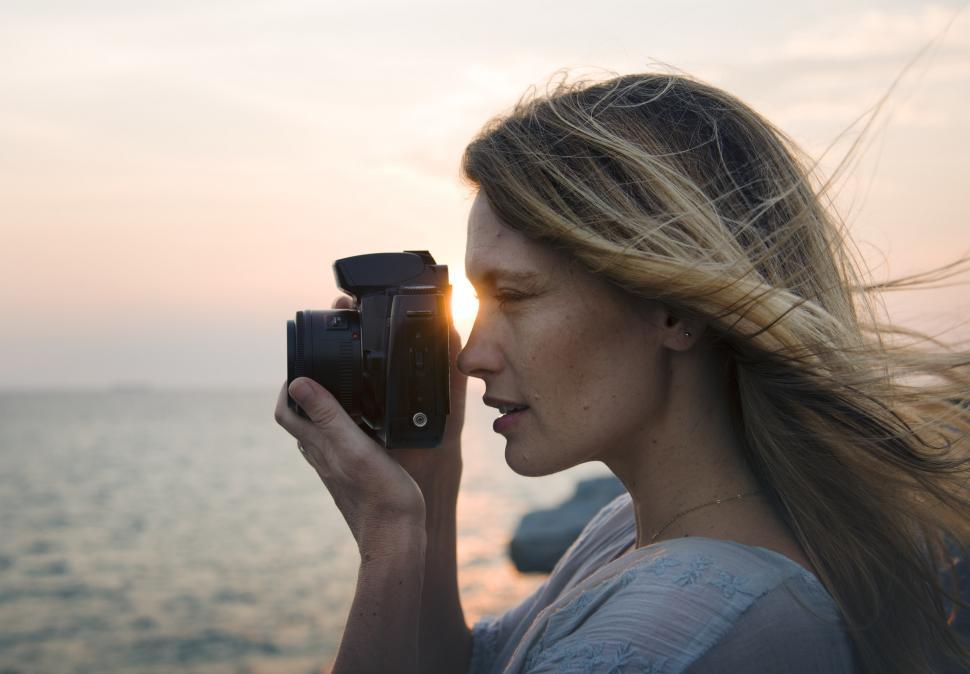 Free Image of A young caucasian woman taking photograph at a seashore 