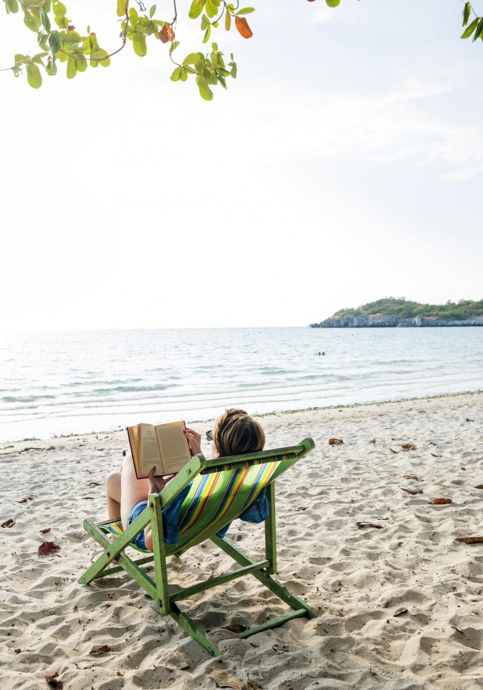 Free Image of A young woman reading book on the beach 