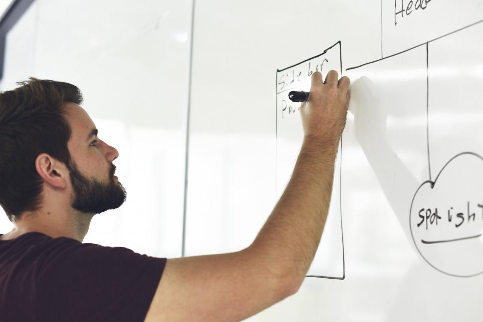 Free Image of A bearded young man creating a flow chart on white board 