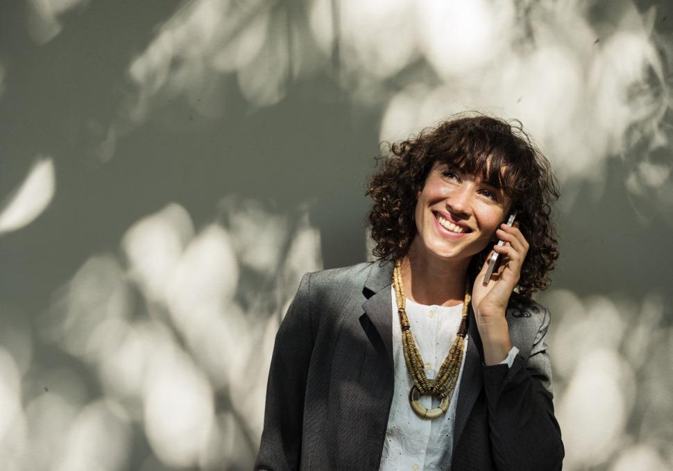 Free Image of A young smiling woman listening to a call on her mobile phone 