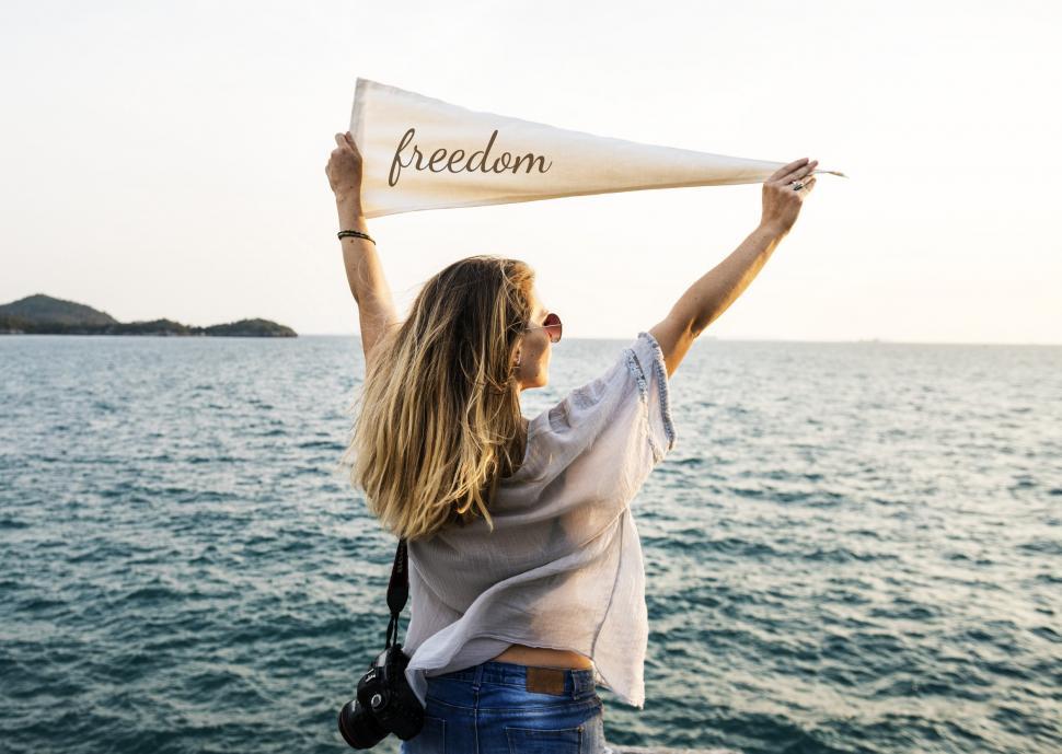 Free Image of A young woman holding white flag high at a seashore 