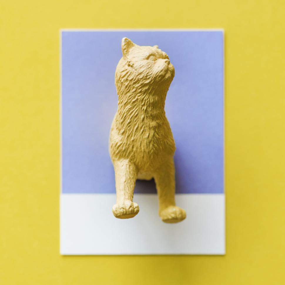 Free Image of Yellow plastic toy cat on a blue and white cardboard 