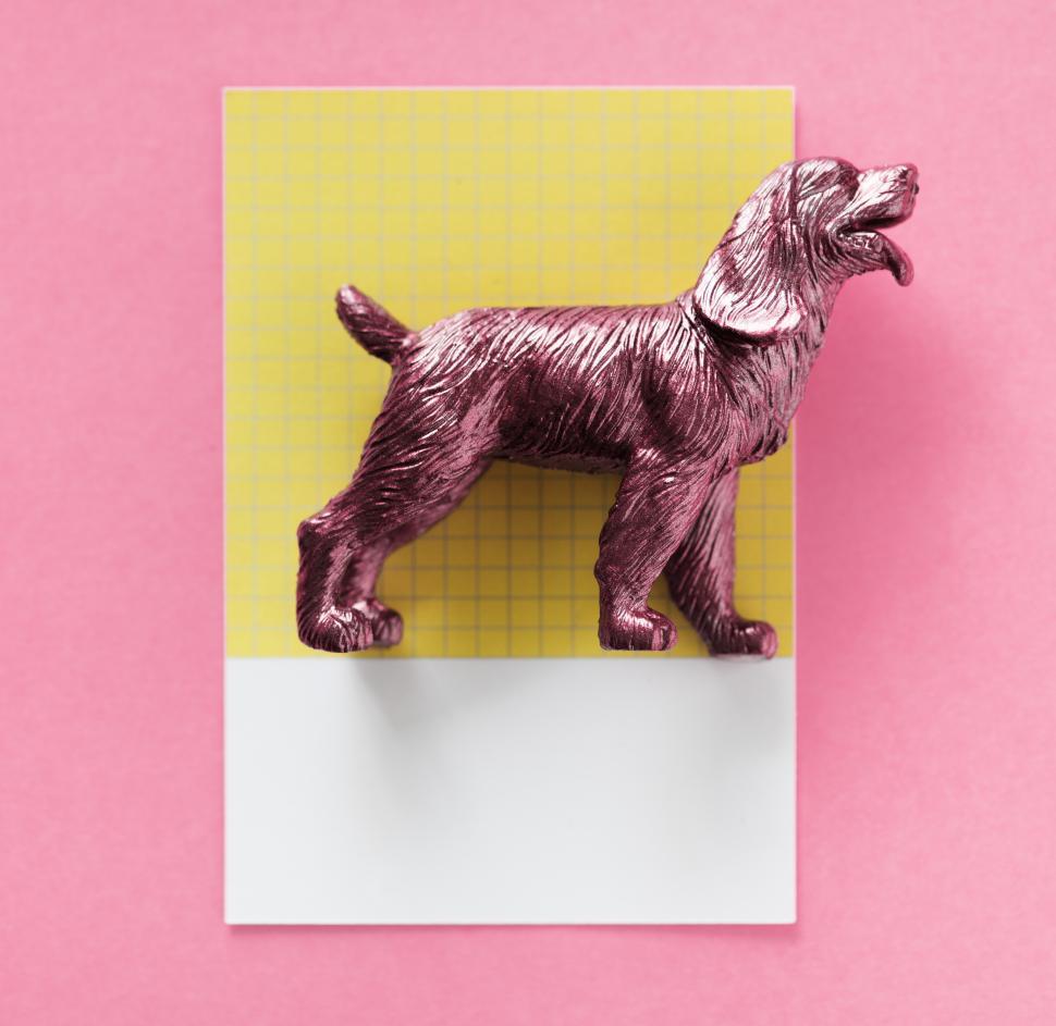 Free Image of Glitter red plastic toy dog on a white and yellow cardboard 