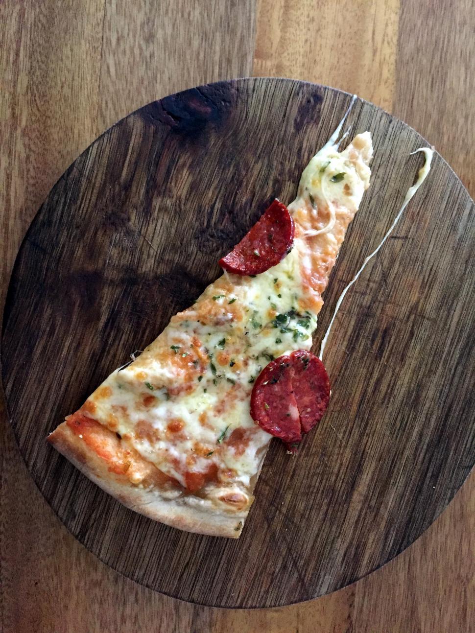 Free Image of A slice of  pepperoni pizza on wooden board 