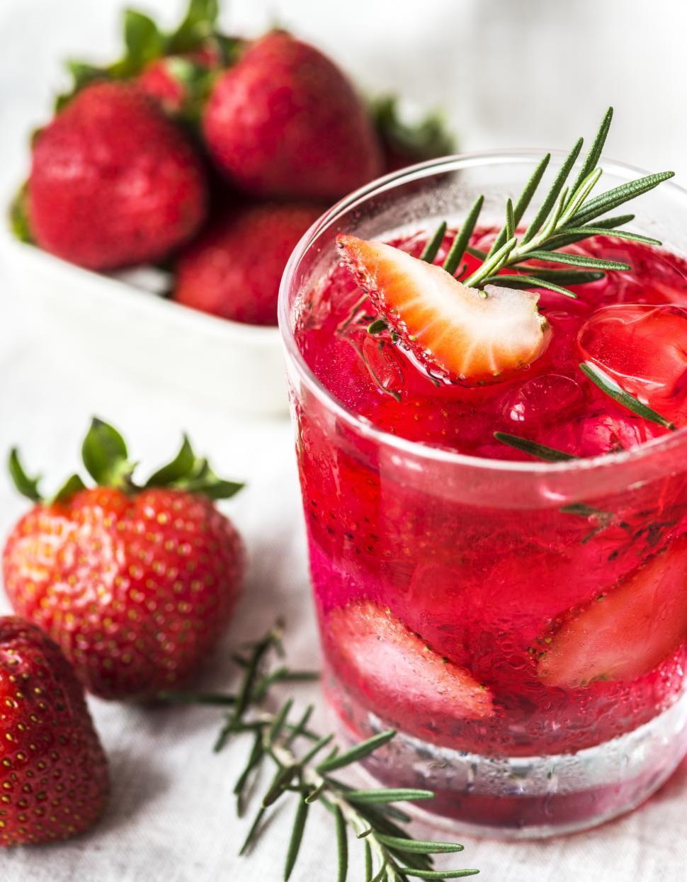 Free Image of Close up of a glass chilled beverage garnished with sliced strawberries 