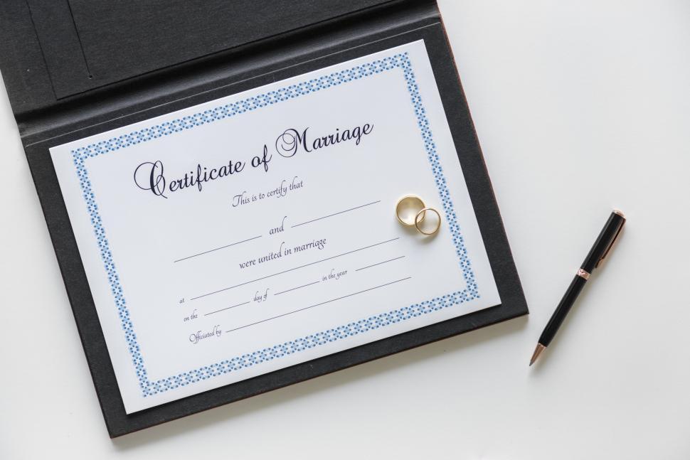 Free Image of A blank Certificate of Marriage with wedding rings and a pen 