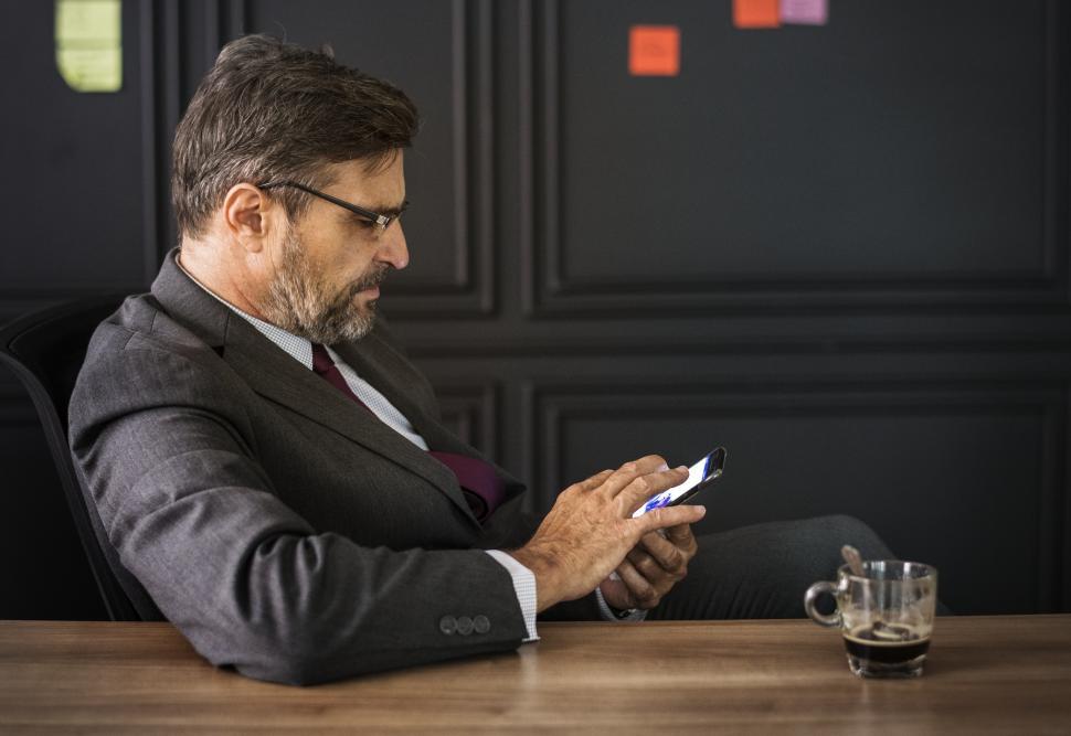Free Image of A bearded businessman looking at his mobile phone 