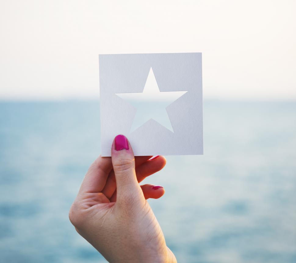 Free Image of A female hand holding a star shaped paper cut out template 