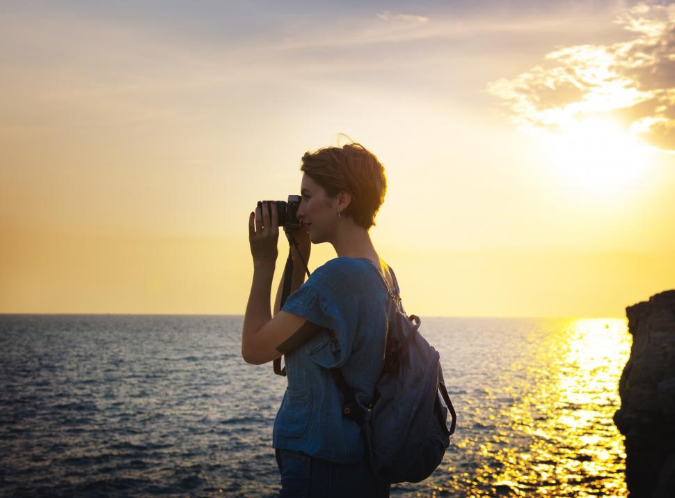 Free Image of A young caucasian woman taking photograph at sunset 