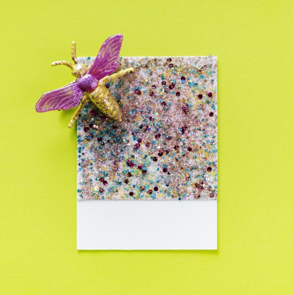 Free Image of Flay lay of a miniature toy fly on a glittery spaced cardboard frame 