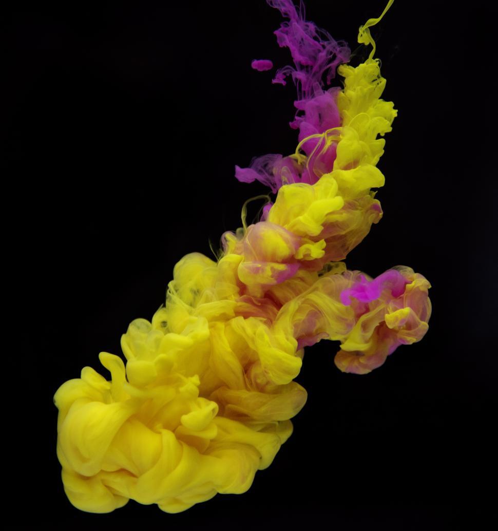 Free Image of An abstract pattern of magenta and yellow ink swirling in water 