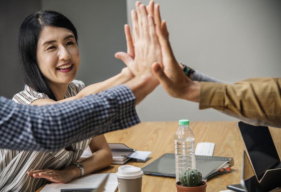 Free Image of Coworkers giving high five over table in the office 