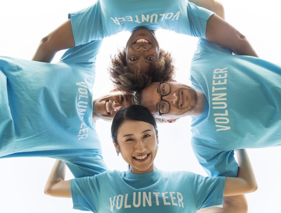 Free Image of Volunteers huddle together, looking down at camera 