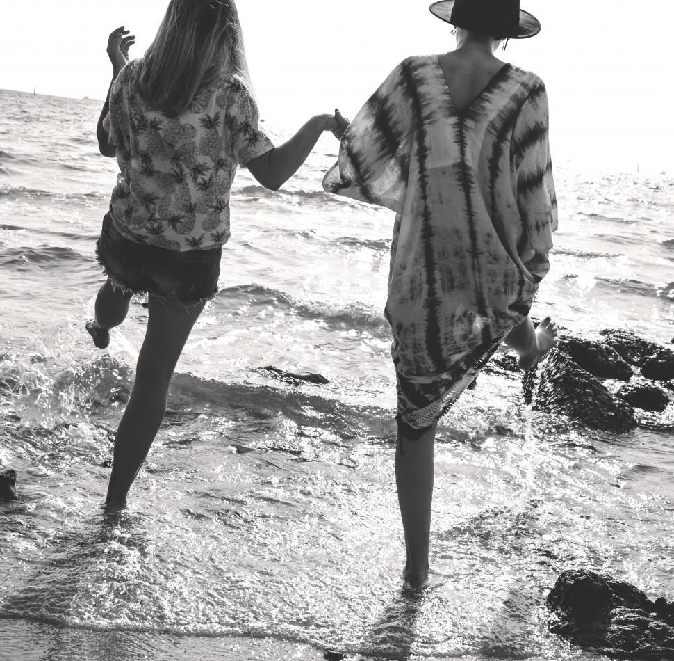 Free Image of Rear view of two Caucasian women splashing seawater with their legs 