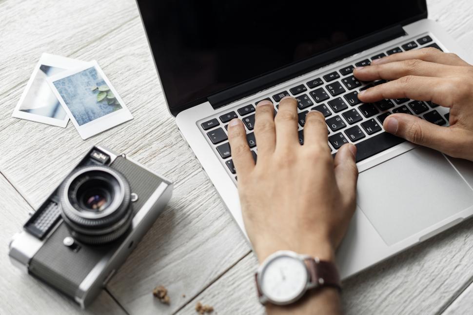 Free Image of Close up of a camera and person typing on laptop 