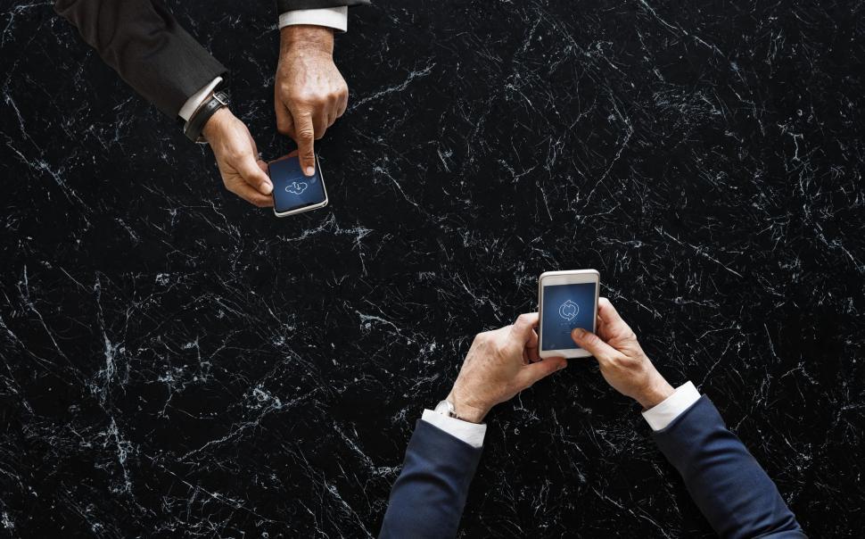 Free Image of People transferring data from one mobile phone to another 