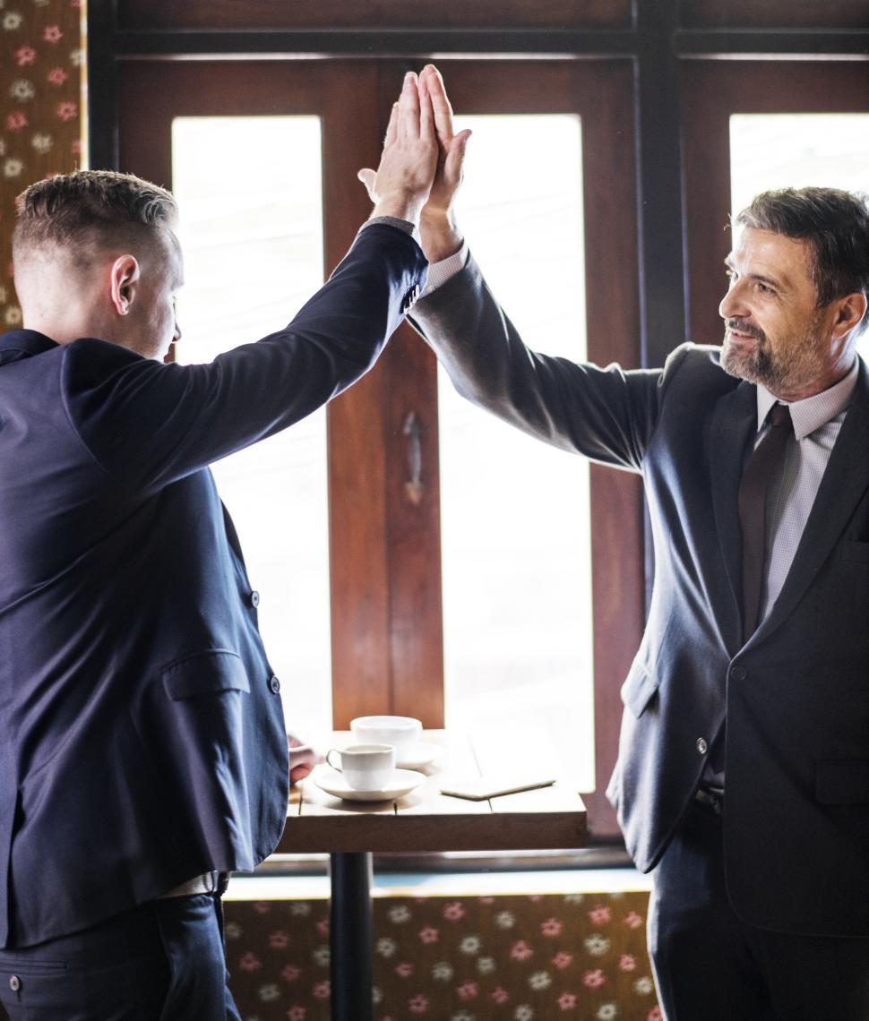 Free Image of Smiling colleagues in suits giving high-five 