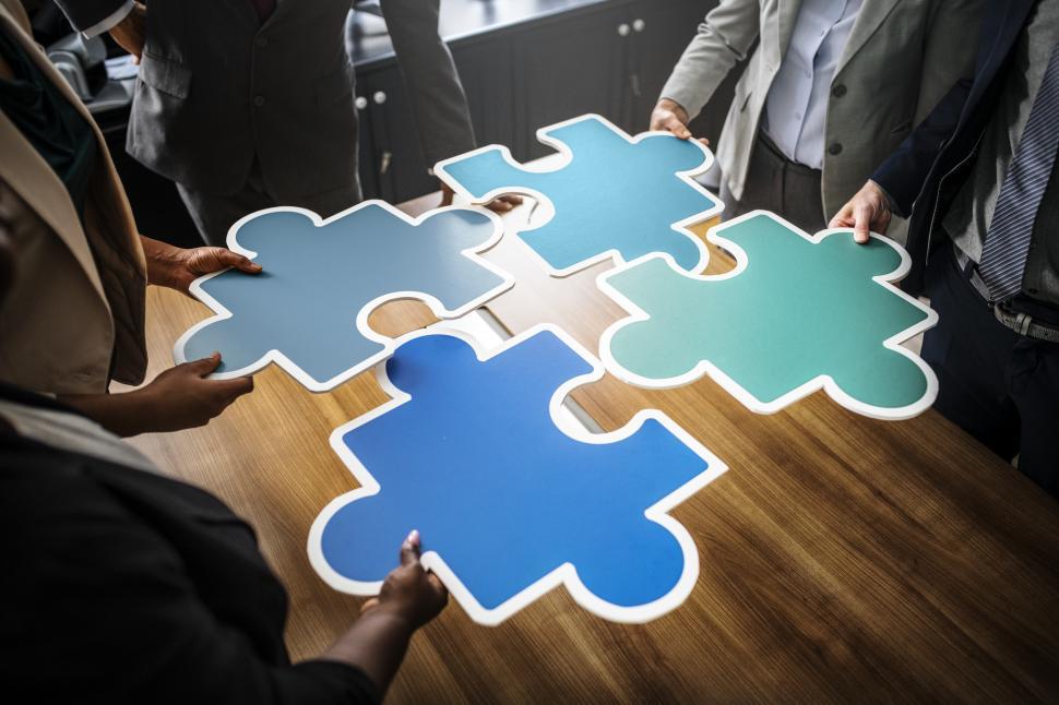 Free Image of A group of colleagues joining big jigsaw puzzle cutouts 