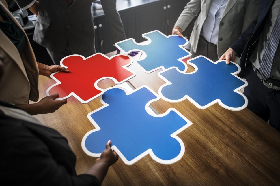 Free Image of A group of colleague joining big jigsaw puzzle cutouts 