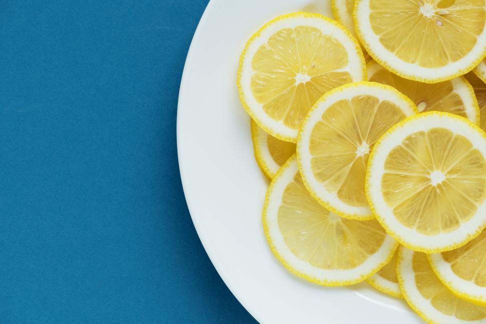 Free Image of Flat lay of lemon slices on white plate, blueish background 