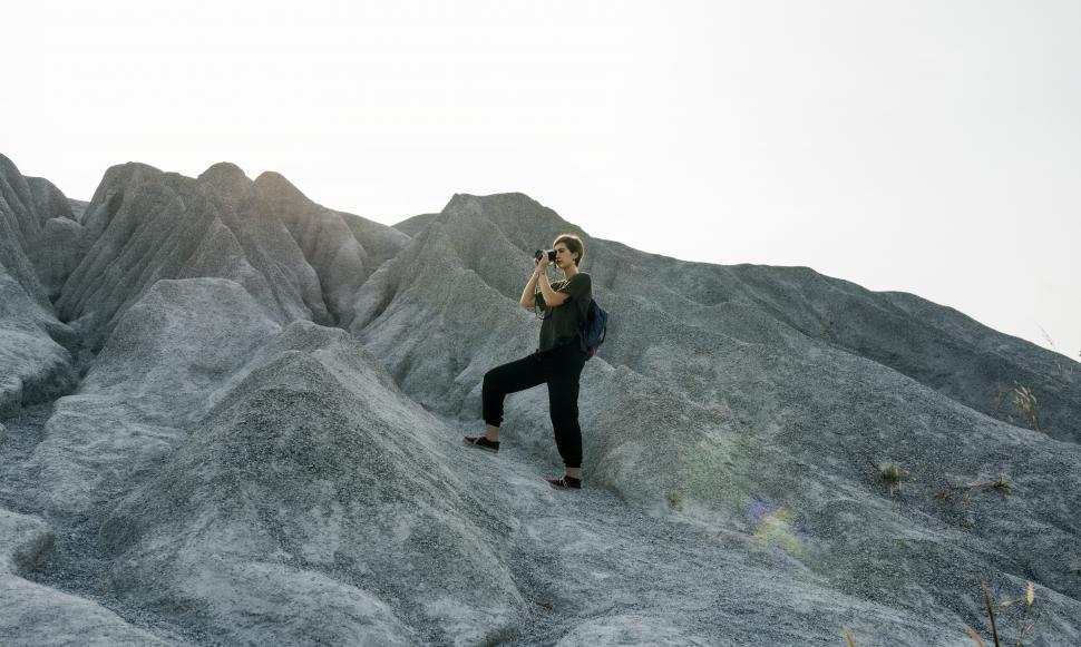 Free Image of A young caucasian woman taking photo during a bumpy hike 