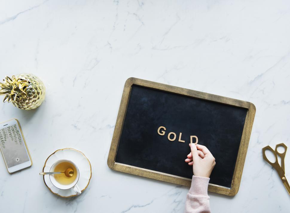 Free Image of Overhead view the word GOLD being arranged on a slate with glittery alphabet blocks 