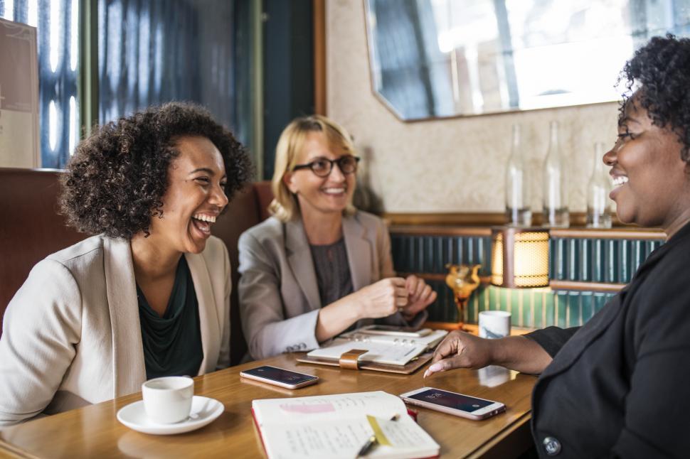 Free Image of Smiling and laughing woman coworkers at a cafe 