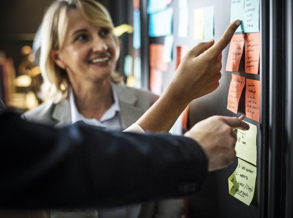 Free Image of A Caucasian woman looks at sticky notes on the notice board 