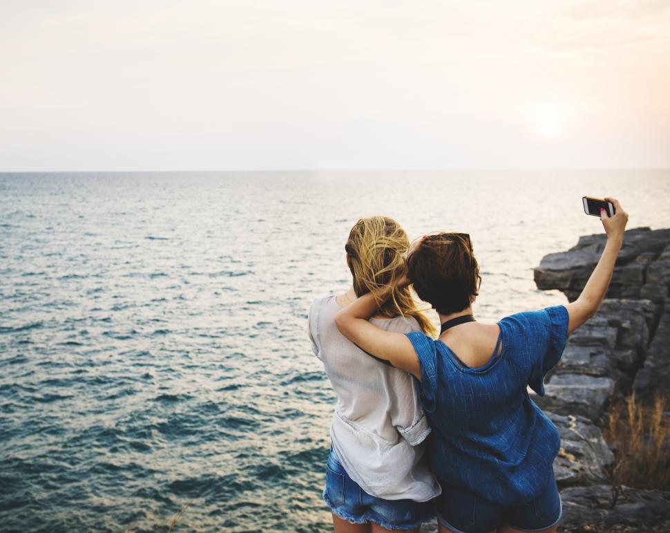 Free Image of Two young women taking selfie at a rocky seashore 