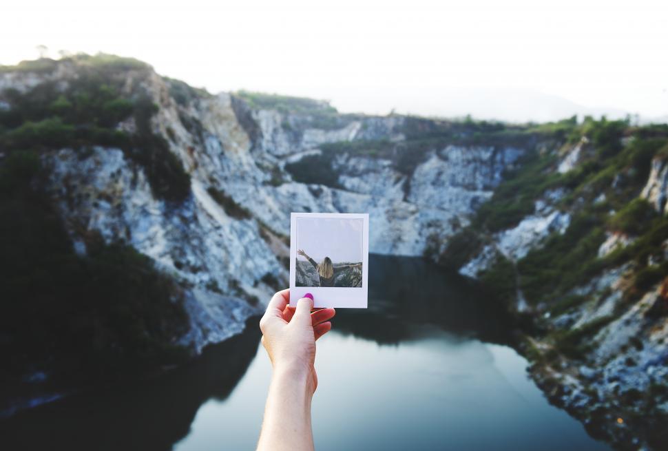 Free Image of Hand holding an instant photograph in front of mountains 