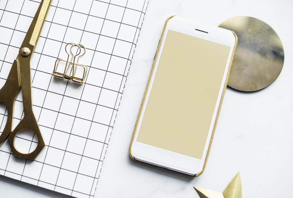 Free Image of Flat lay of a mobile phone alongside a notebook and scissors 