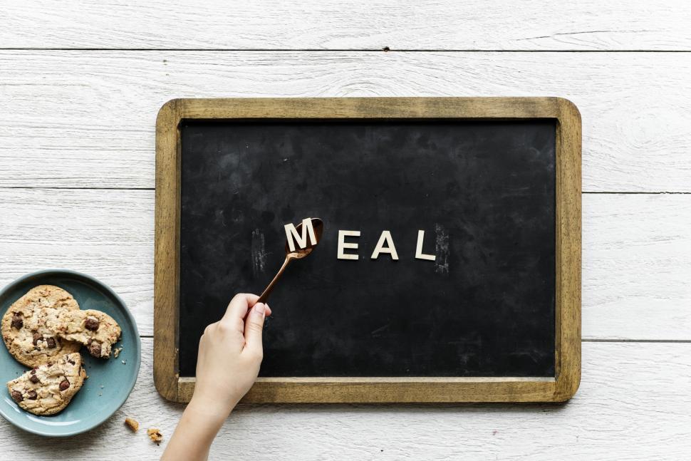Free Image of Overhead view of word MEAL written with plastic alphabet blocks being arranged on a slate with spoon 
