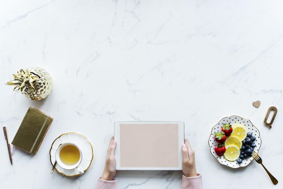 Free Image of Overhead view of hands holding a tablet PC over the white marble surface 