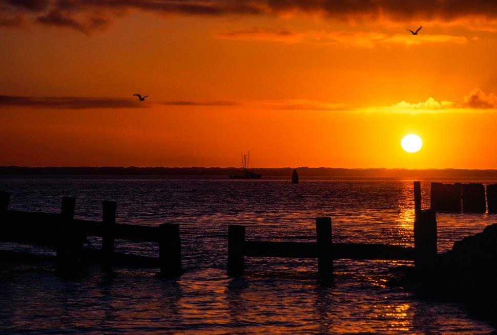 Free Image of Setting sun over pilings and ocean 
