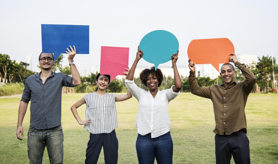 Free Image of A group of multiethnicity colleagues raising colorful cardboard speech bubble cutouts 