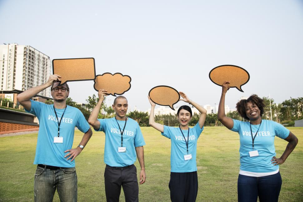 Download Free Stock Photo of A group of multiethnicity colleagues raising various cardboard speech bubble cutouts 