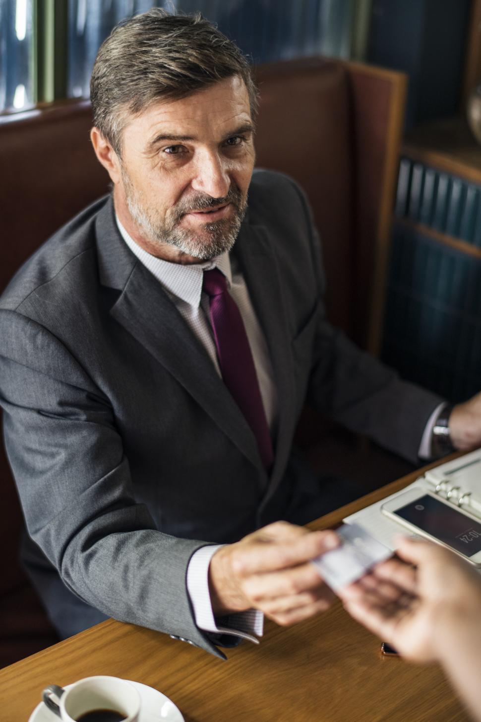 Free Image of A mature business man paying with his card at a cafe 