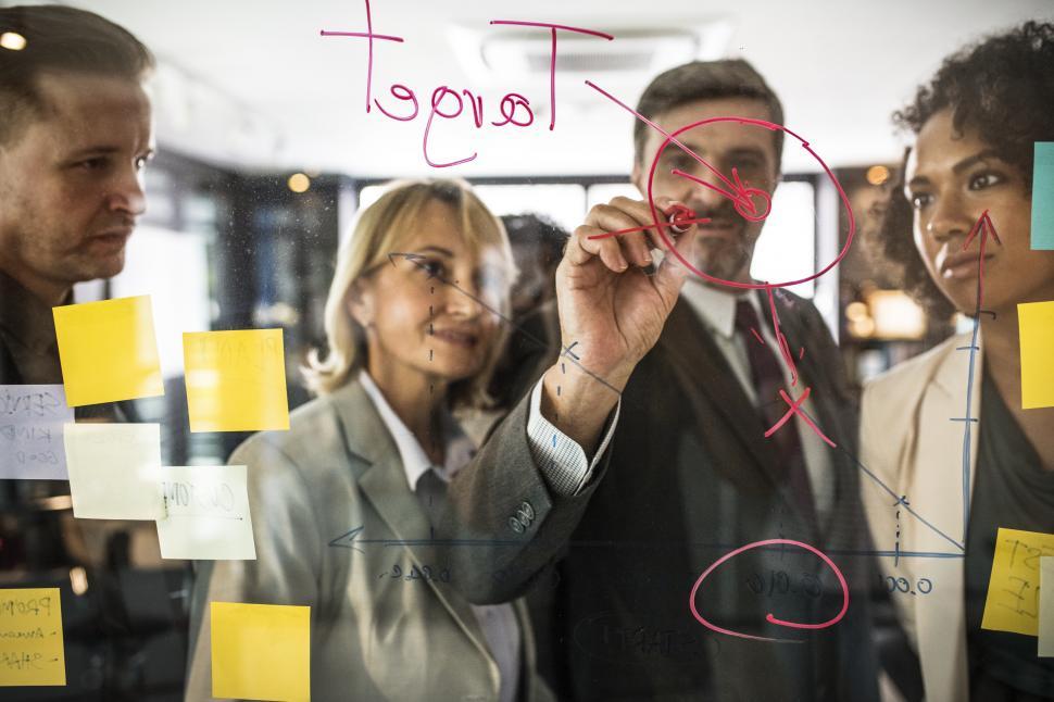 Free Image of A bearded Caucasian businessman drawing a graph on the glass panel 