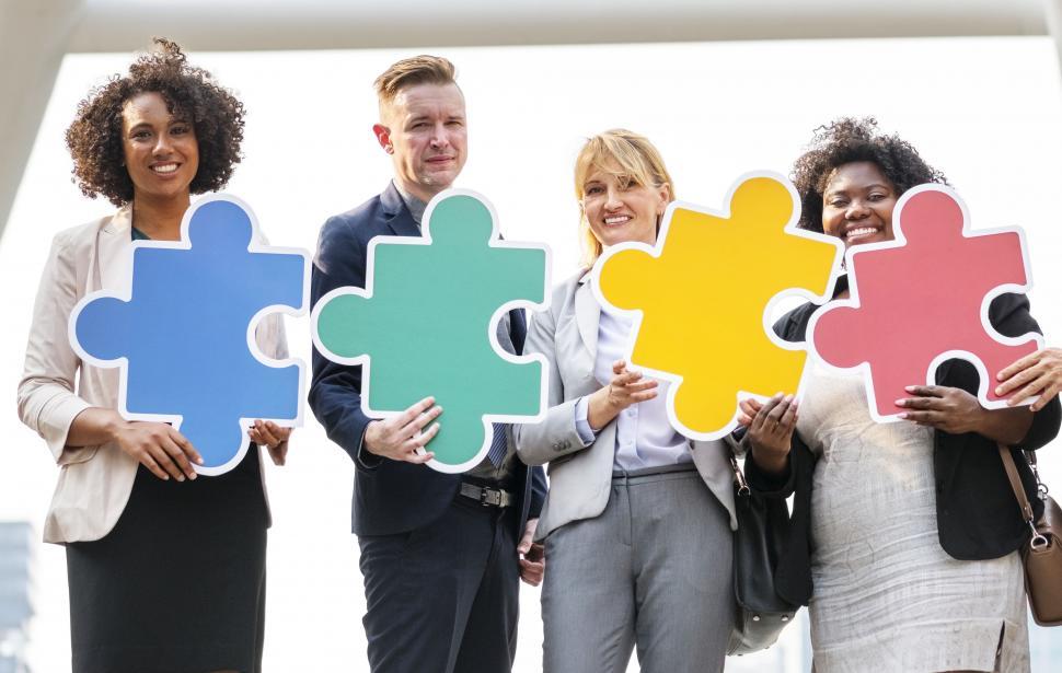 Free Image of A group of coworkers holding cardboard jigsaw puzzle cutouts 