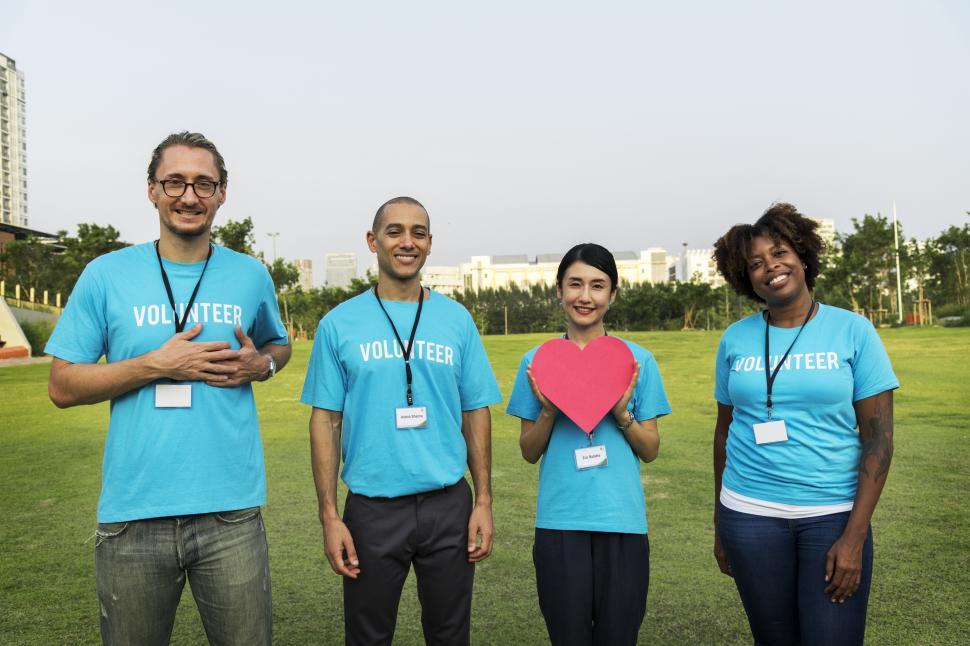 Free Image of A group of volunteers posing with a heart shaped cardboard cutout 