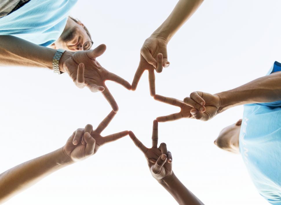 Free Image of Low angle view looking up at volunteers forming a star with fingers 