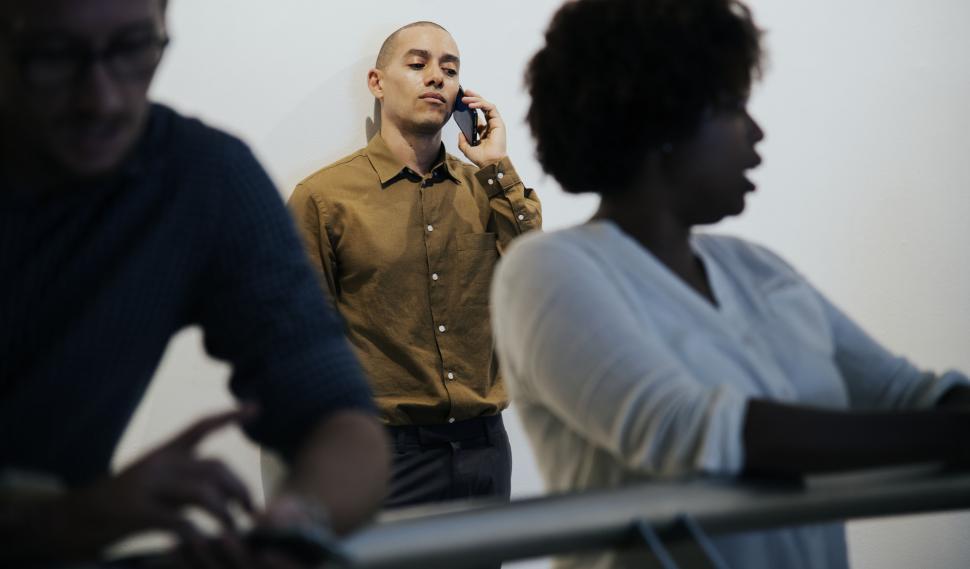 Free Image of A man at the back of the room calling on his mobile phone 