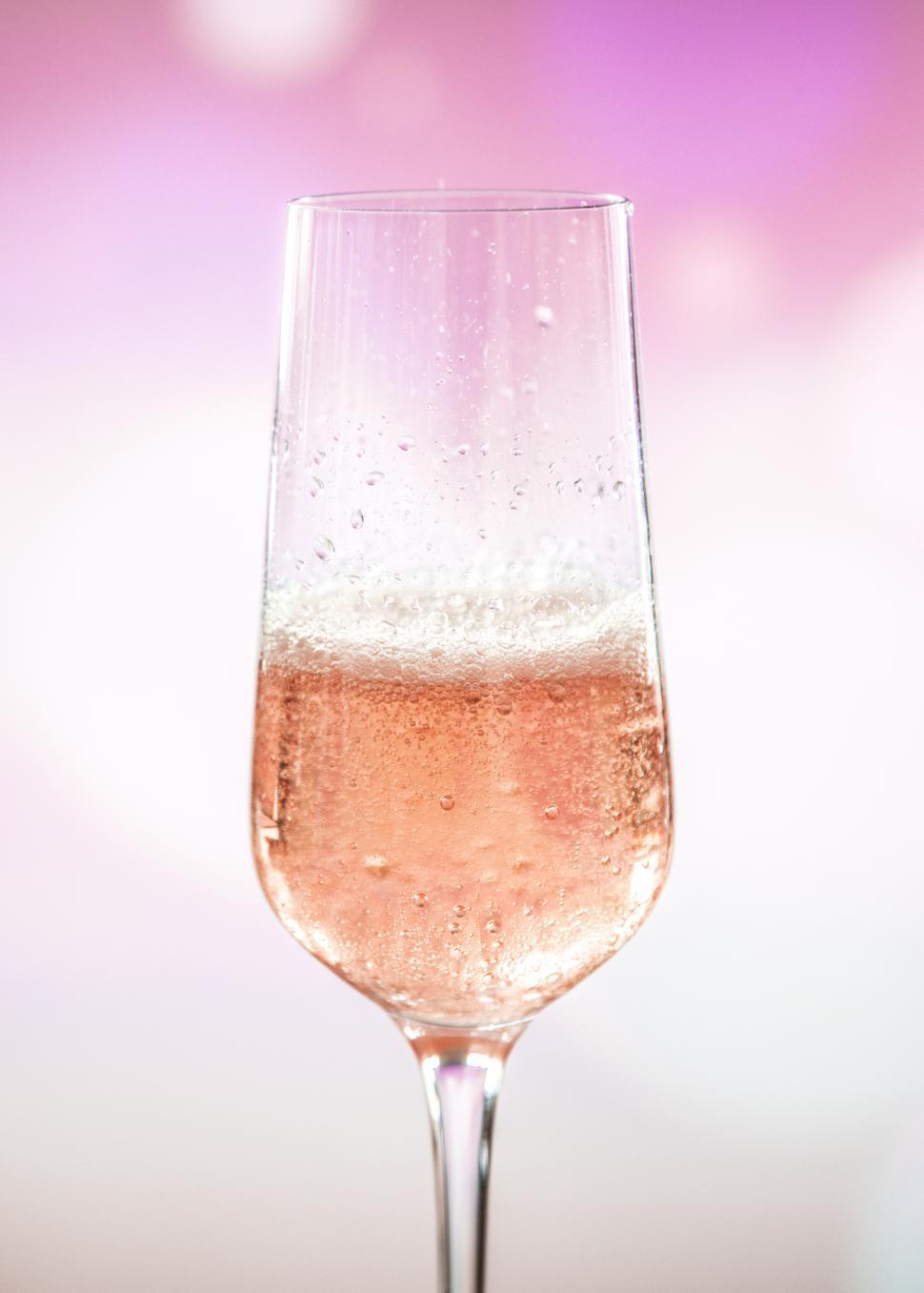 Free Image of Close up of a champagne glass with pink and white background 