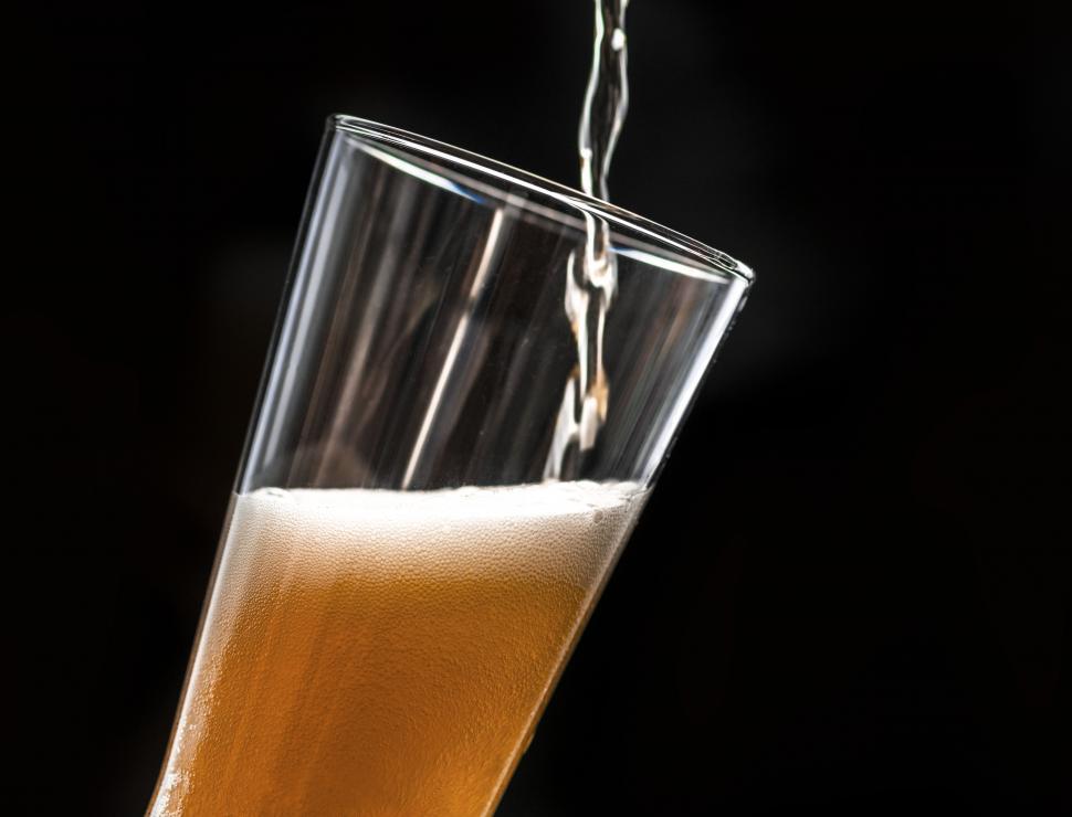 Free Image of Beer being poured into a pint glass, black background 