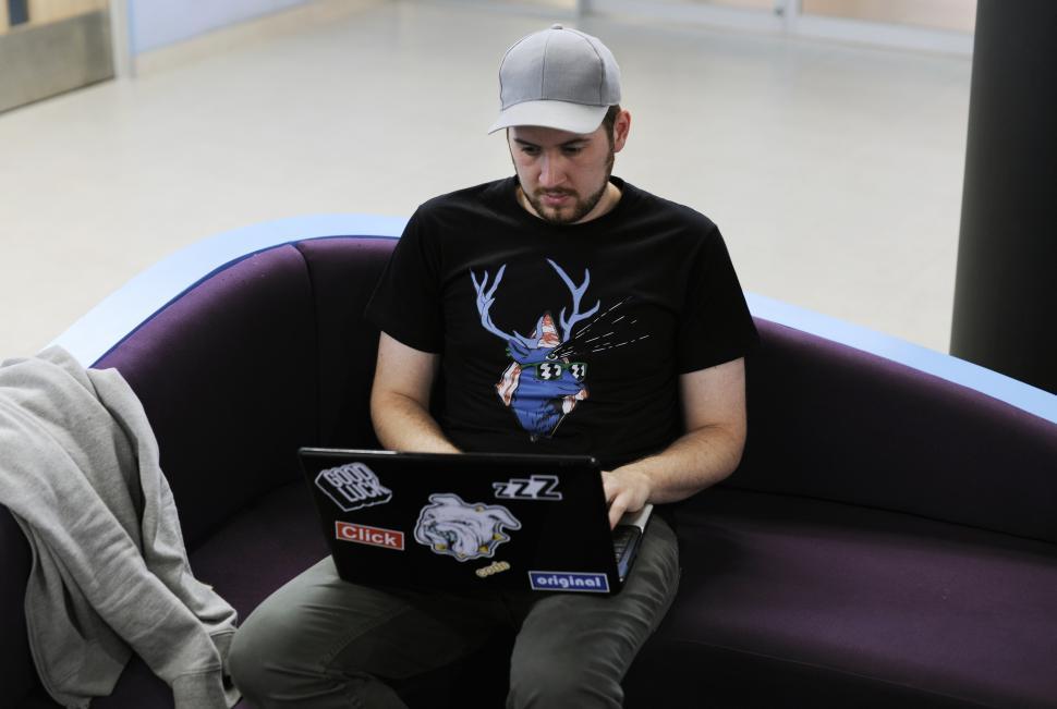 Free Image of A young man sitting on the couch working on his laptop 