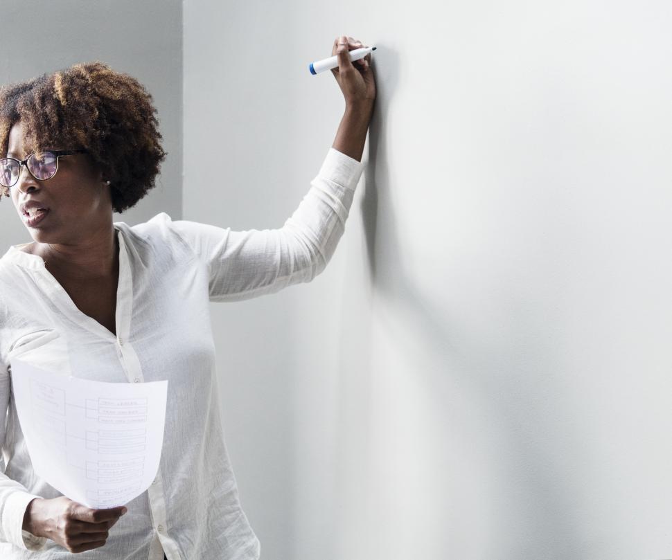 Free Image of An woman writing on the board, looking at audience 