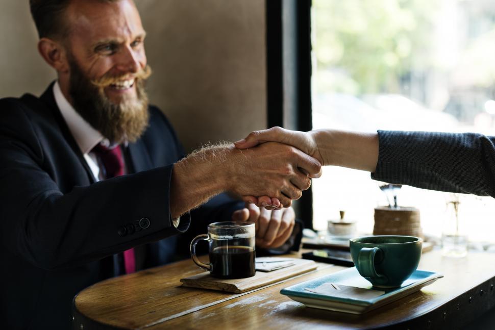 Free Image of Bearded man shaking hands at a table 