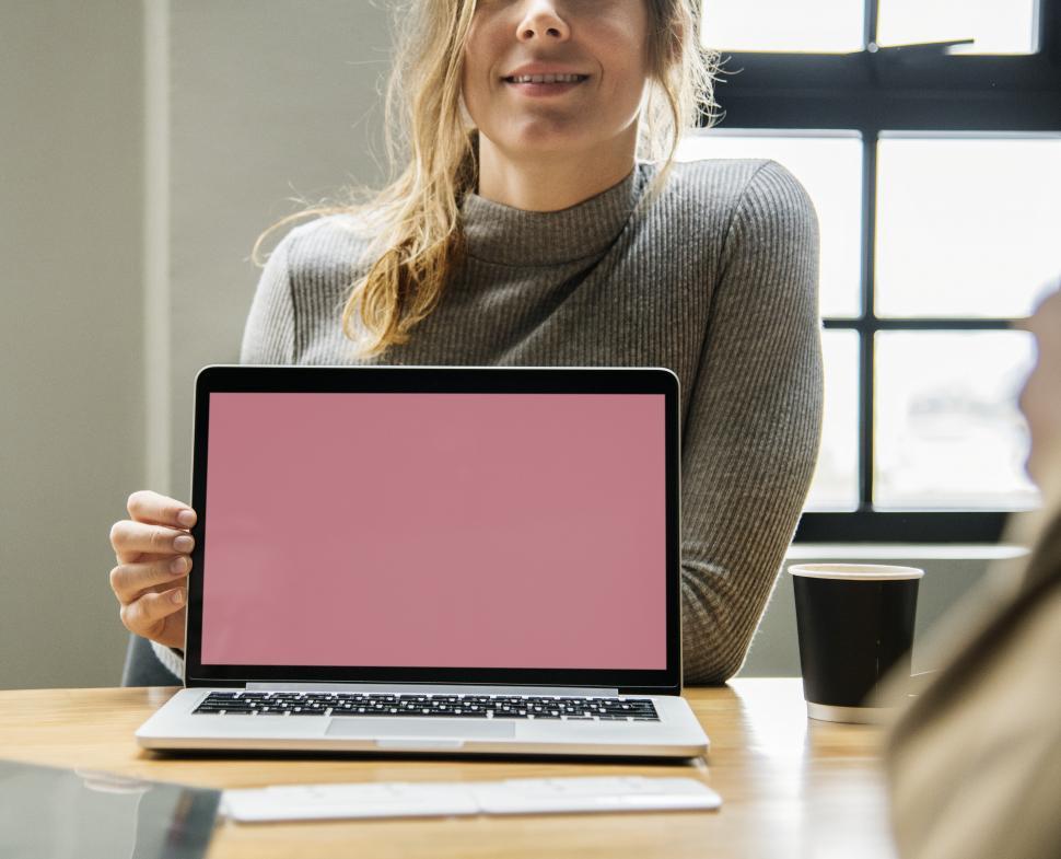 Free Image of A young Caucasian woman showig a laptop - blanks screen 