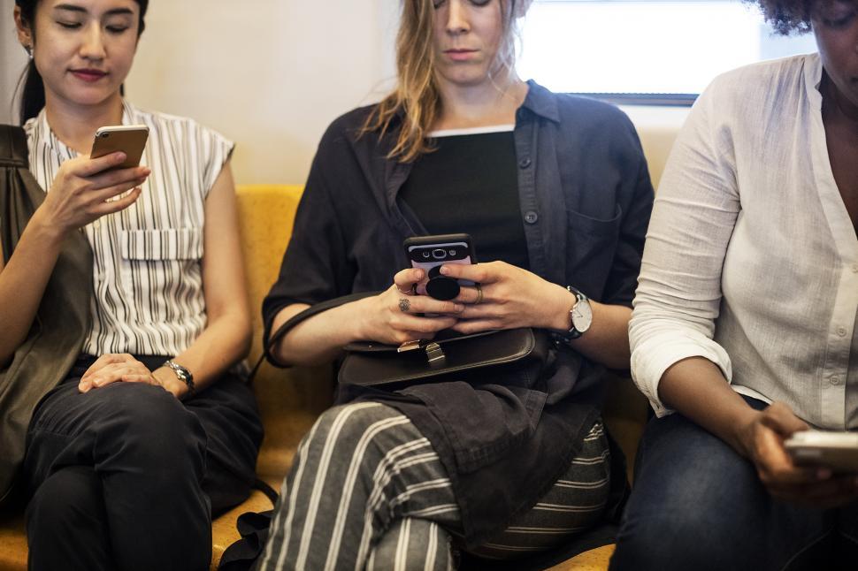 Free Image of Three women on a train, looking at phones 
