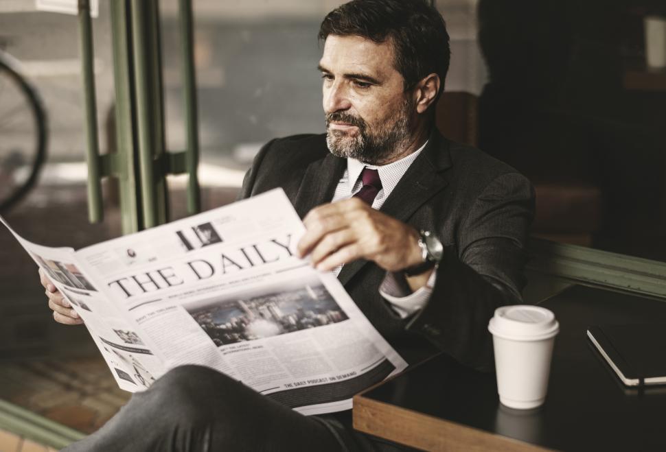 Free Image of A bearded businessman reading daily newspaper 